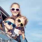 kids wearing sunglasses hanging out car window