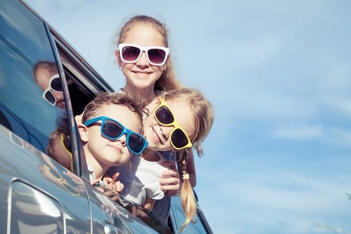 kids wearing sunglasses hanging out car window