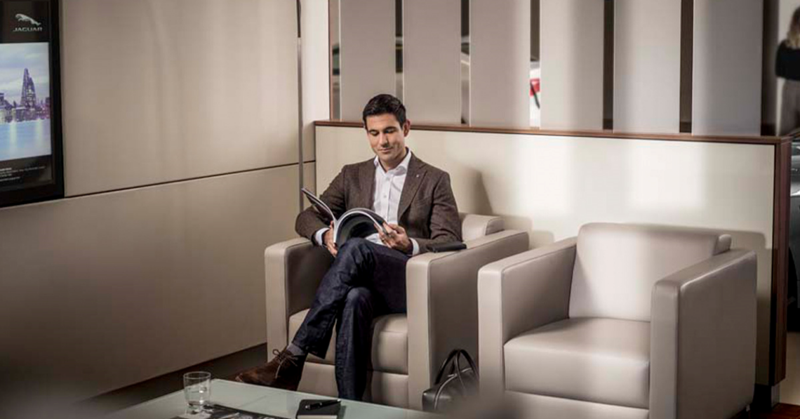 Man waiting at a Jaguar dealership lounge