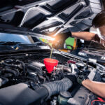 Technician pouring oil into an engine