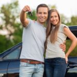 Couple standing in front of a new car